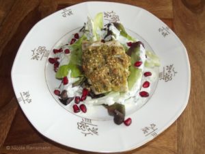 Fisch mit Sesam-Senf-Kruste auf Minisalat mit Granatapfelkern und Joghurtsauce.
